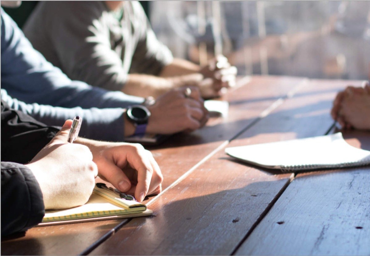 Twee mensen in overleg aan een tafel met notitieboek