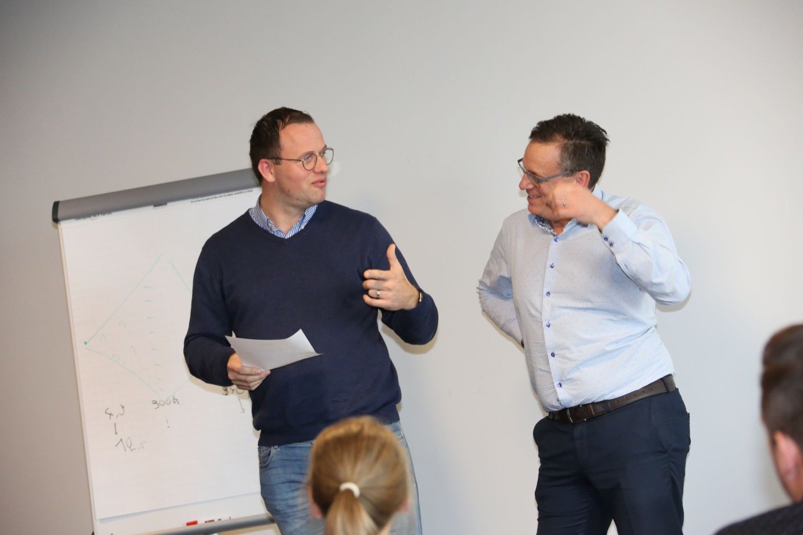 Twee KMO-bedrijfsleiders bespreken hun strategie bij een flipchart tijdens het groepstraject strategisch leiderschap
